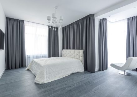 Minimalistische slaapkamer met grijze gordijnen en wit bed