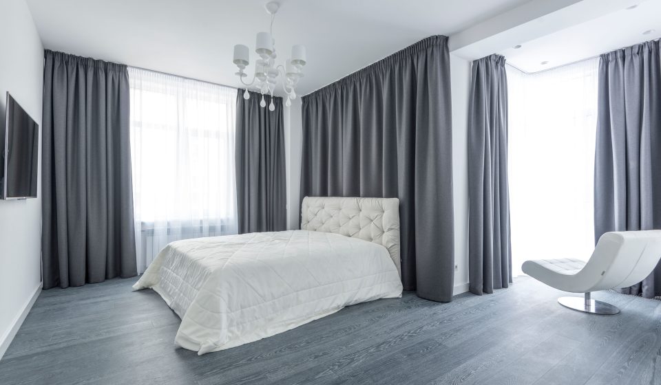 Minimalistische slaapkamer met grijze gordijnen en wit bed