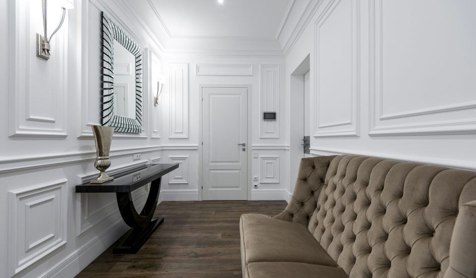 Wit interieur met tufted bank en klassieke muurpanelen