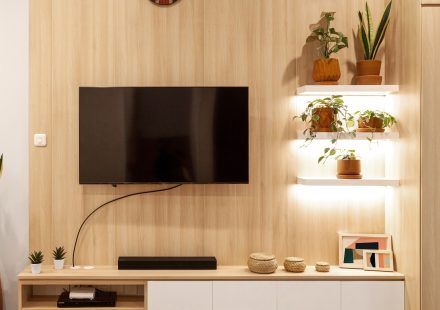 Woonkamer met aan de muur gemonteerde tv, houten planken en planten