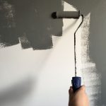 Hand verft een muur grijs met een roller
