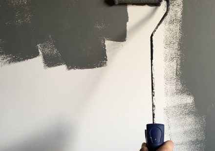 Hand verft een muur grijs met een roller